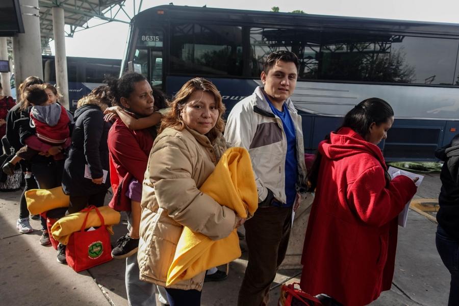 A migrant mother and son wait to board the bus at a bus station.
