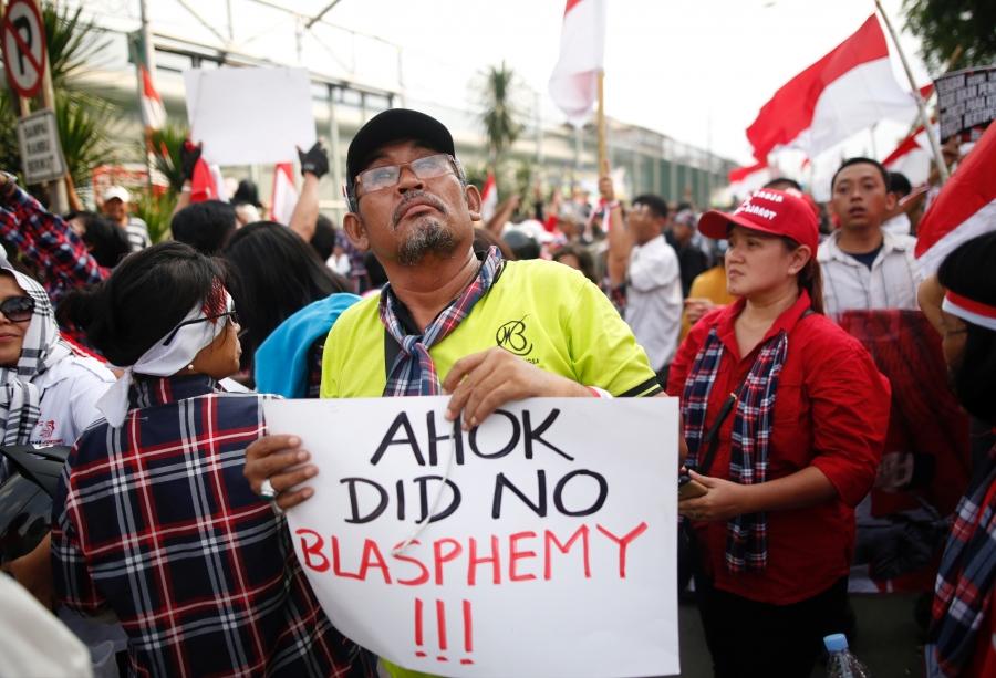 Protesters in support of Ahok hold sign that he didn't commit blasphemy