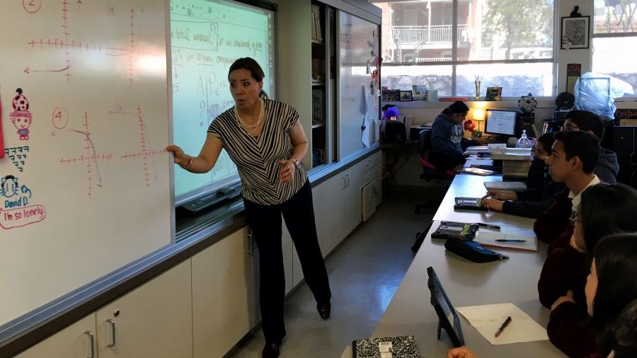 A teacher stands at the front of a classroom