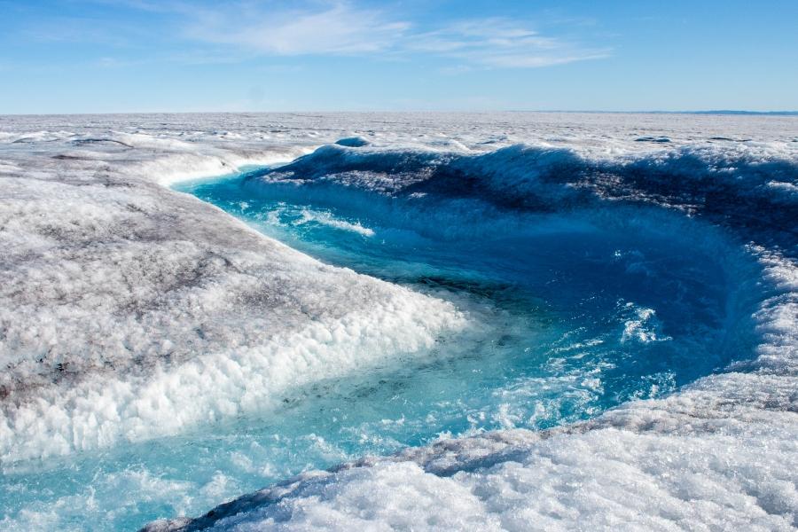 A winding flow of water is shown on the Greenland ice sheet