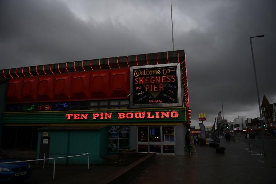 The facade of a bowling alley is shown illuminated with neon lights. 