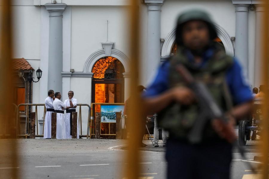 An armed man stands guard with priests in the background
