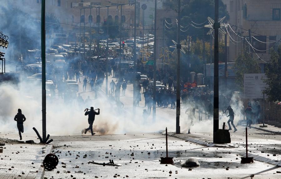 Palestinian protesters run for cover from tear gas fired by Israeli troops during clashes at a protest, in the West Bank city of Bethlehem Dec. 7, 2017.