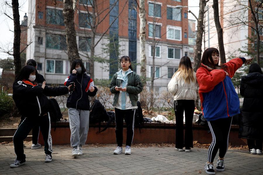 Young women are shown doing dance moves in an outdoor park.