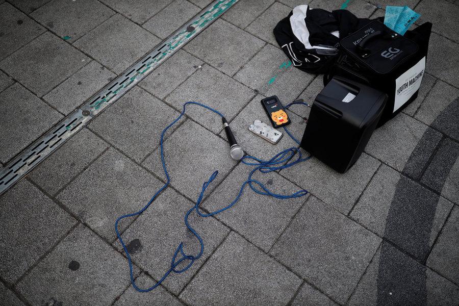 A microphone is shown laying on the ground connected to a small amplifier.