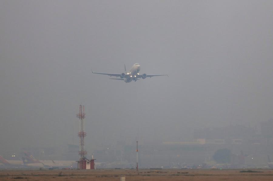 A plane takes off in smog
