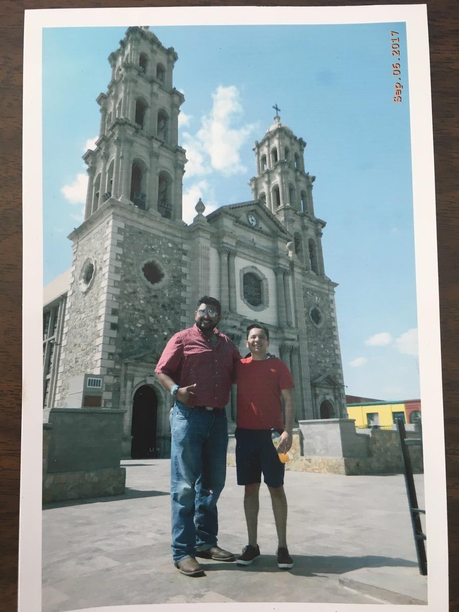 Two men pose in front of elaborate cathedral
