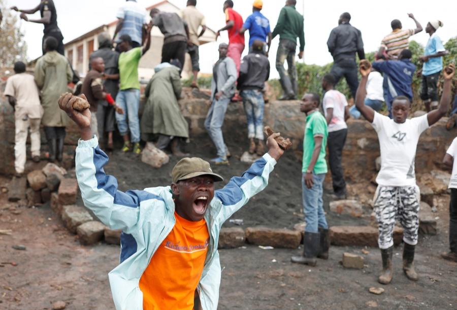 An opposition supporter with rocks in his hands is seen shouting in the Kibera slum.