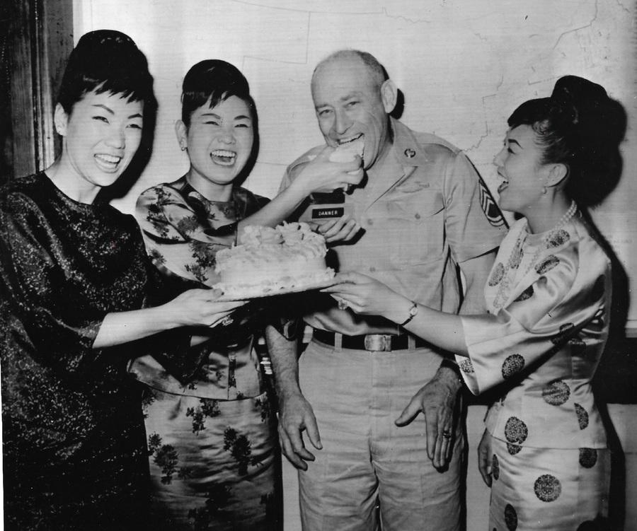 Three Korean women and one man in a military uniform laugh over cake