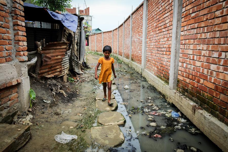 A child walks through the road, which has no drainage facility and all wastes from hanging toilet go directly to the road