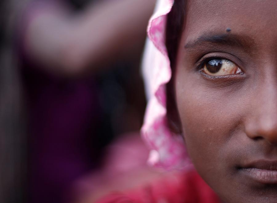 A Rohingya refugee girl waits to be taken to a refugee camp