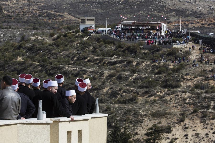 Members of the Druze community look at their friends and relatives on the Syrian side of the border, during a rally in the Druze village of Majdal Shams on the Israel-occupied Golan Heights, Feb. 14, 2014. 