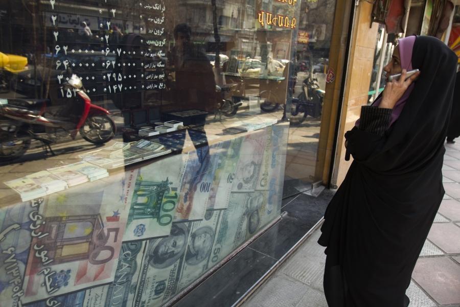 A woman looks through a window decorated with large currency notes