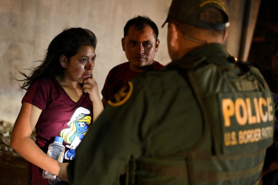 A young girl is shown standing in front of a Border Patrol officer and crying.