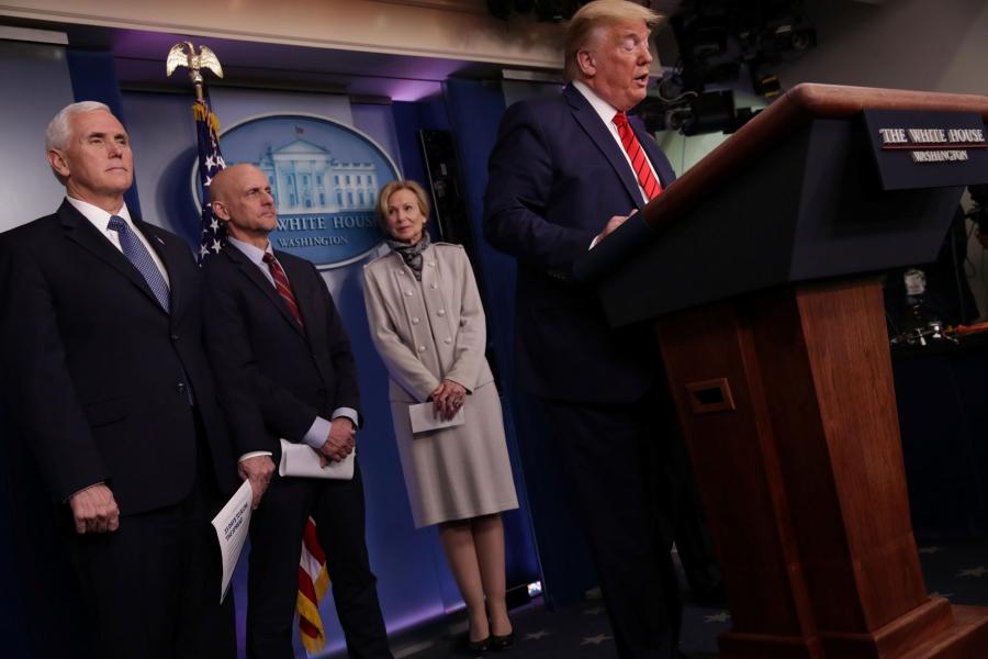 President Trump stands at a White House podium with officials behind him. 