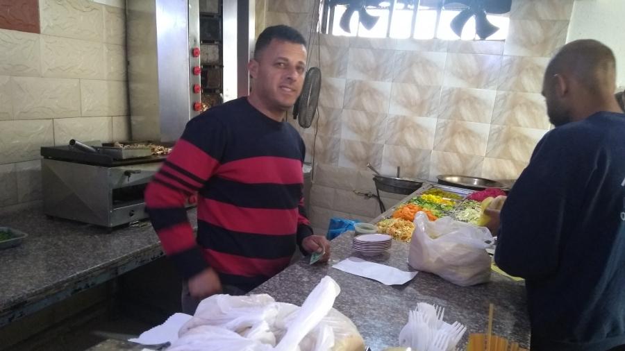 Two men stand at the counter preparing falafel at the Fence café in Baka al-Gharbiyeh. 