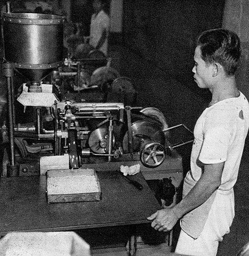 A man stands by a machine in this black and white photo