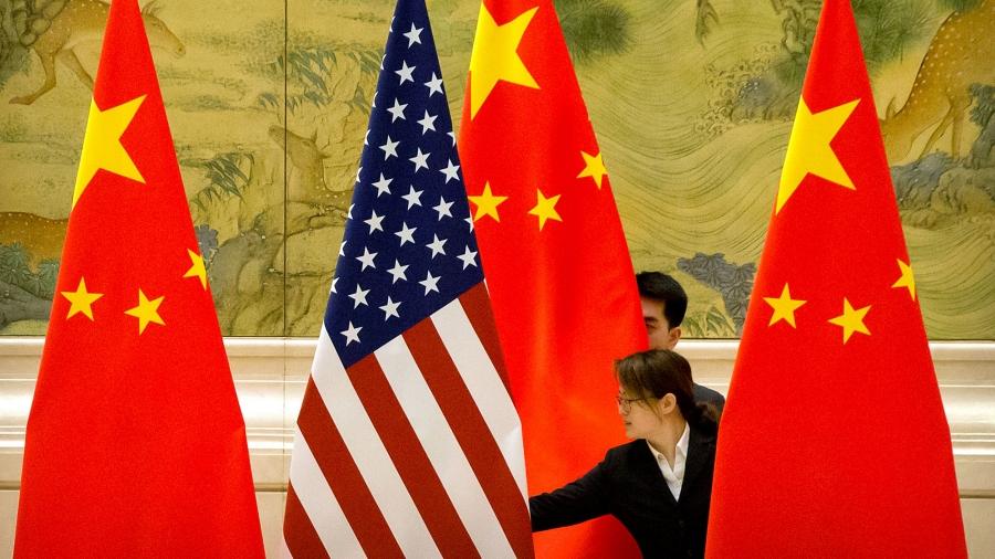 One US and three Chinese flags are shown being straightened by a woman standing in the middle of them.