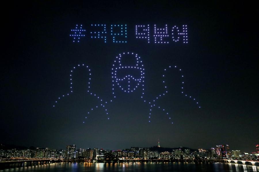 Drones fly over the sky of Seoul creating the image of medical workers in protection gear.