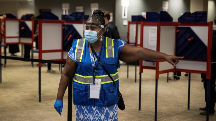 A poll worker directs voters to cast their ballots for the upcoming presidential election as early voting begins in Cincinnati, Ohio, Oct. 6, 2020.