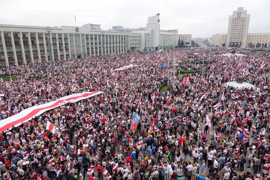 A massive crowd of people gather for a protest in the Belarusian capital. The nation's flag colors, red and white, are apparent throughout the photo. 