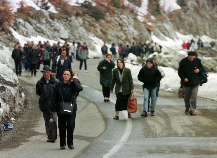 A large group of people walking on a mountainside road. 