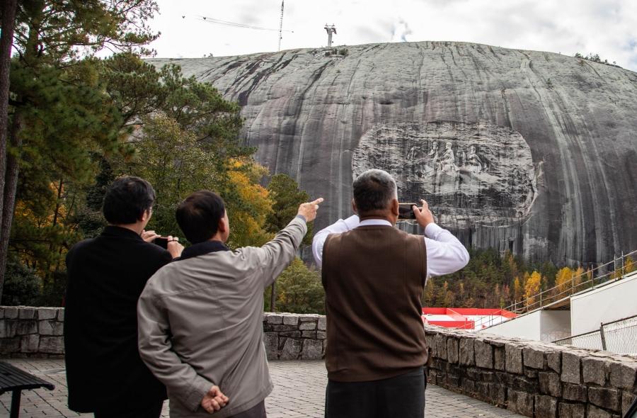 Tourists point at and take cell phone photos of Stone Mountain.