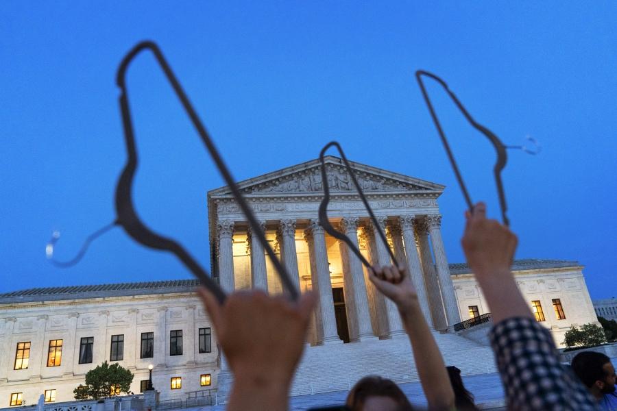 Demonstrators hold coat hangers in the air as they protest outside of the U.S. Supreme Court in May 2022. 