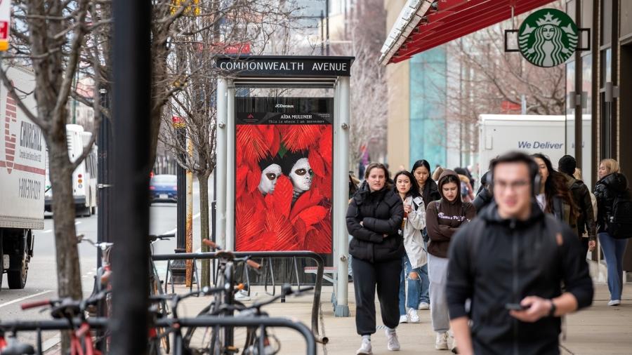Aïda Muluneh's "If they come for me in the morning" is shown at a bus stop in Boston, Massachusetts as commuters walk by.