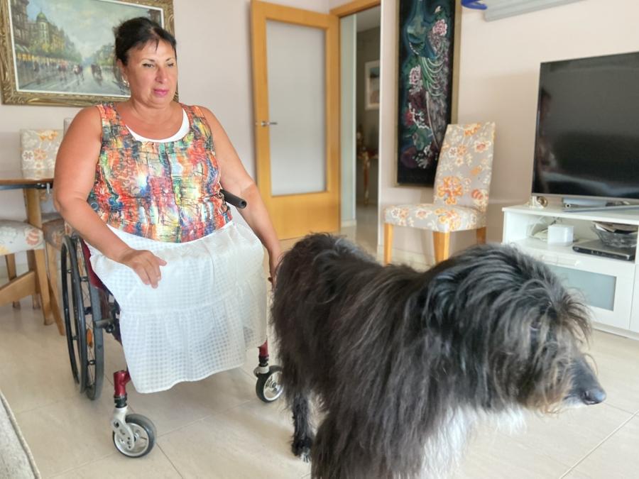 woman in wheelchair with black dog beside her