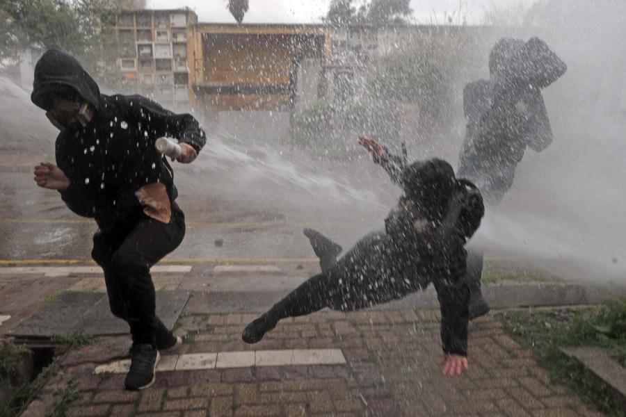 people in black running and walling from a water hose