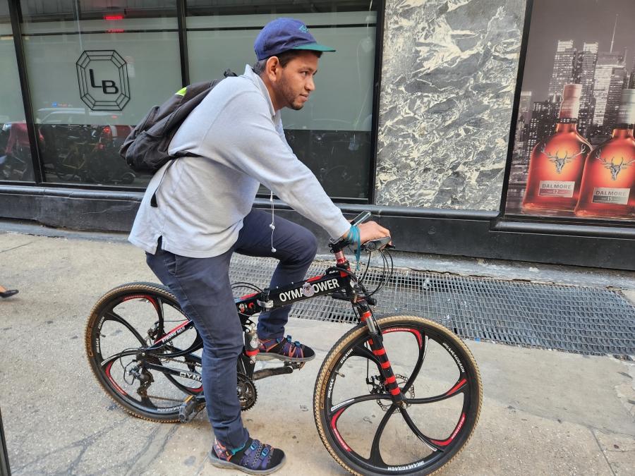 A man wearing a had and gray hoodie on a bike in the city
