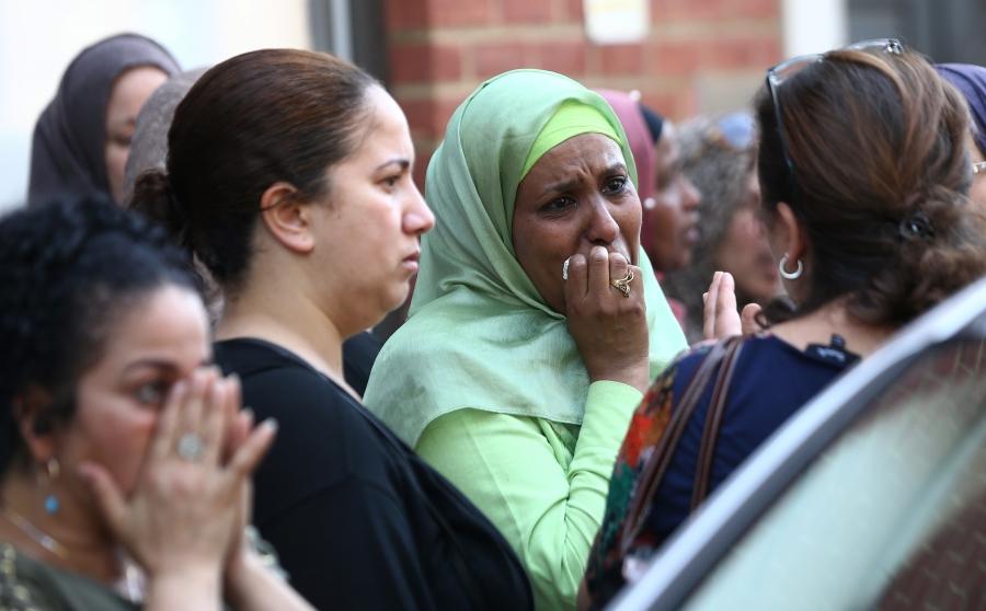 People react near a tower block severely damaged by a serious fire, in north Kensington