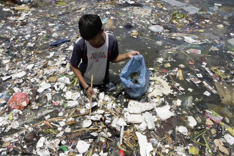 A boy collects plastic near a polluted coastline to sell in Manila, April 9, 2008. 