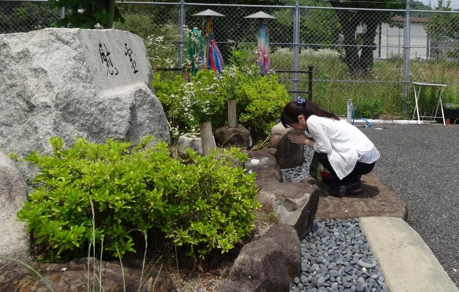 Aya Kano pays her respects at a shrine to the dead of Ninoshima.