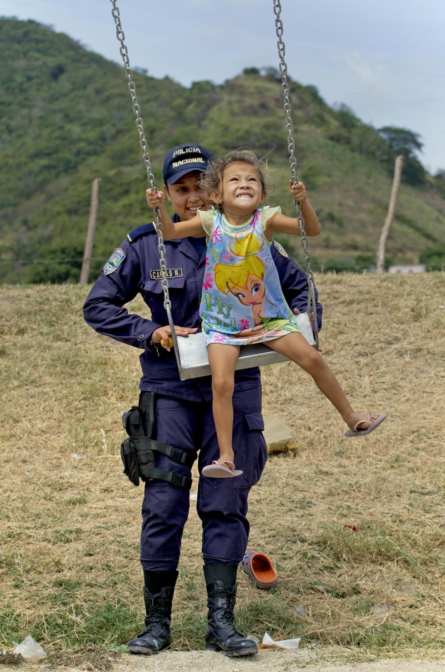 Honduran police officer Julisa Carias gives Jireh López, 4, a push on a swing in Chamelecón, a neighborhood in San Pedro Sula.