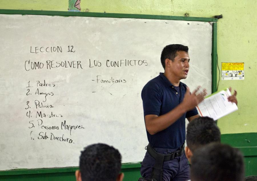 A police officer talks about resolving conflicts as part of a program called GREAT (Gang Resistance Education and Training) with students in Chamelecón, San Pedro Sula, Honduras.