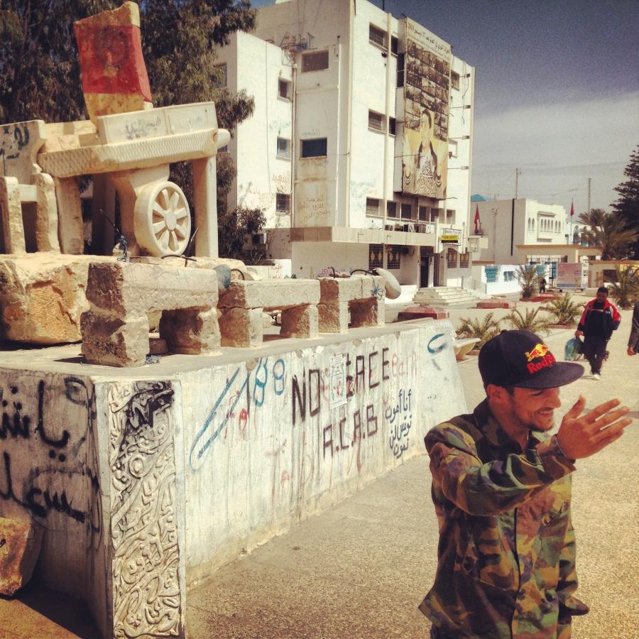 Nidhal Bouallagui in his hometown of Sidi Bouzid. He stands in front of the memorial for Mohamed Bouazizi, who set himself on fire on December 17, 2010 after an argument with the police. His desperate act triggered national protests and led to the overthr