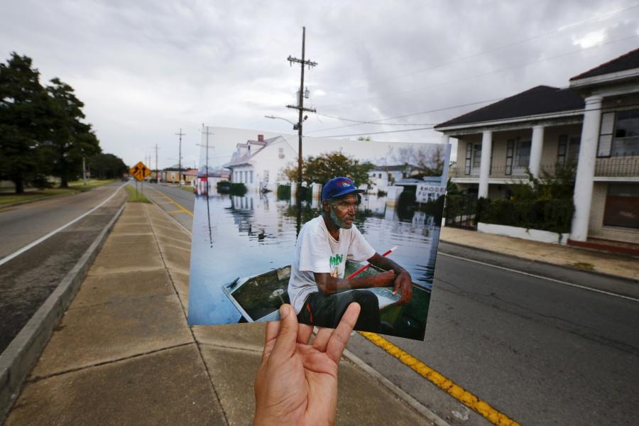Photographer Carlos Barria holds a print of a photograph he took in 2005, as he matches it up at the same location 10 years on, in New Orleans. The print shows Errol Morning sitting on his boat on a flooded street September 5, 2005, after Hurricane Katrin
