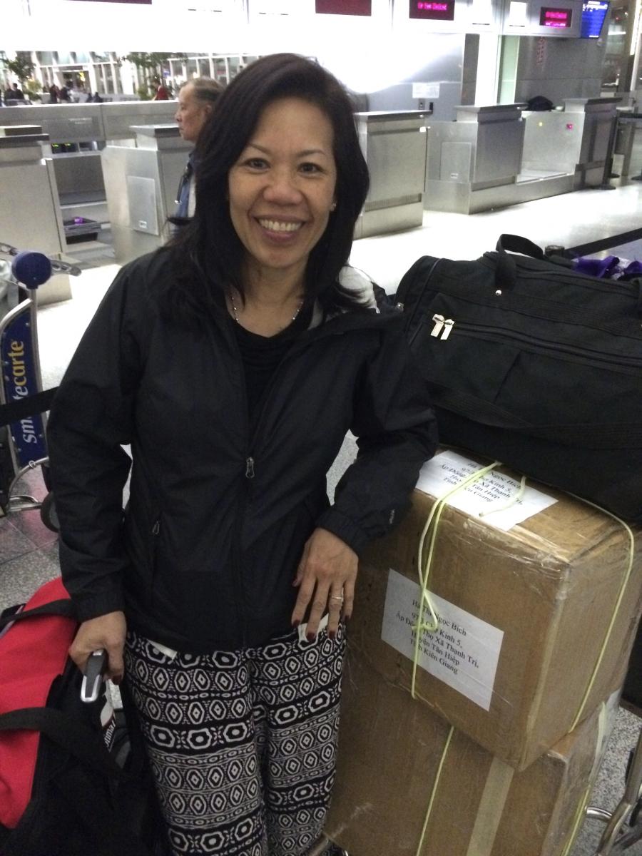 Ngoc Bich Ha stands in front of a conveyor belt with suitcases.