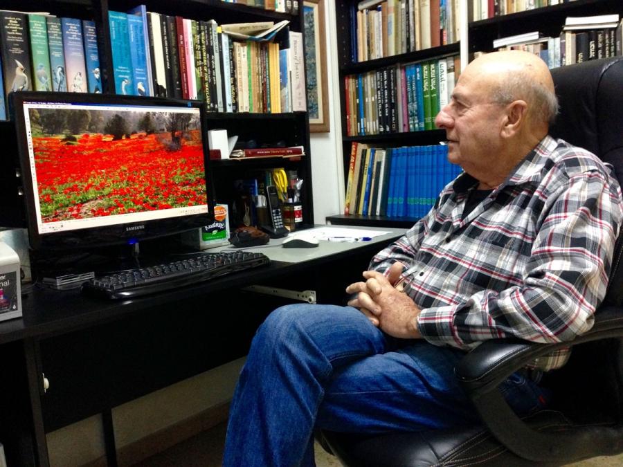 Uzi Paz, an Israeli wildflower expert, looks at a photo of Israeli wildflowers in his home in central Israel. Paz helped drive the campaign in the 1960s to outlaw wildflower picking.