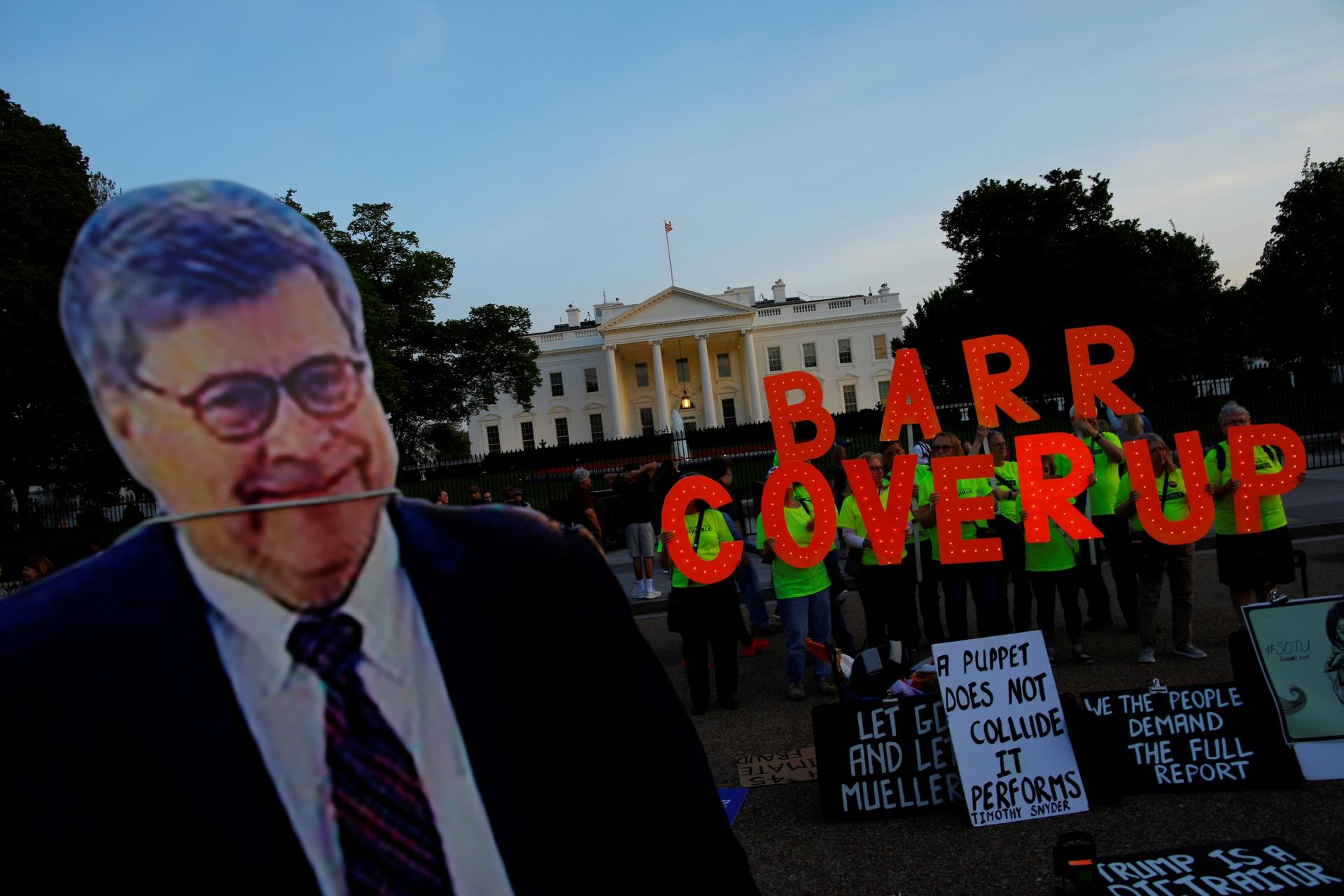 A cardboard cutout of US Attorney General William Barr is seen as protesters hold signs which read "Barr Coverup," following the release of the Mueller report on President Donald Trump at the White House in Washington, DC, April 18, 2019.