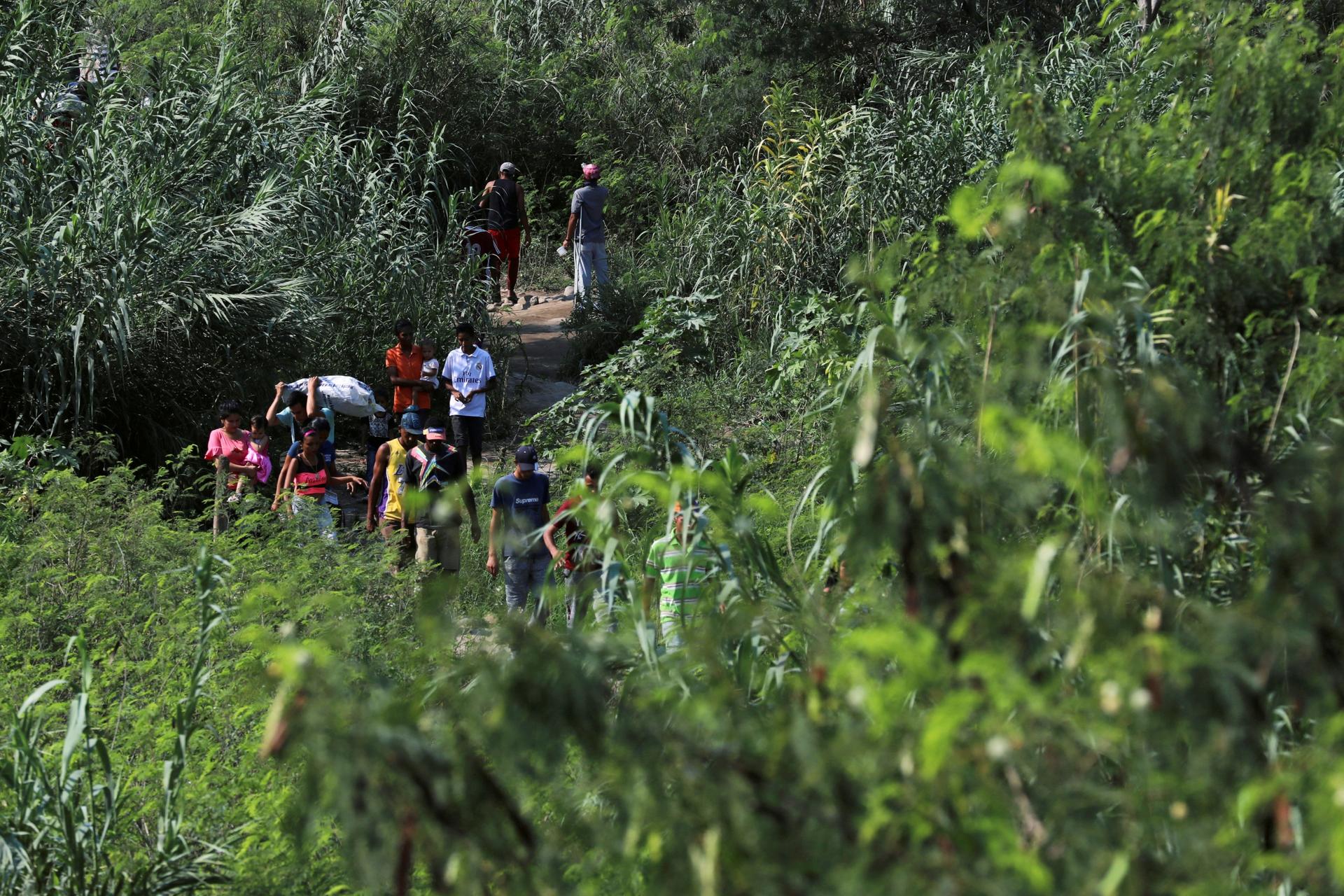 people walk along a path on the  venezuela-colombia border