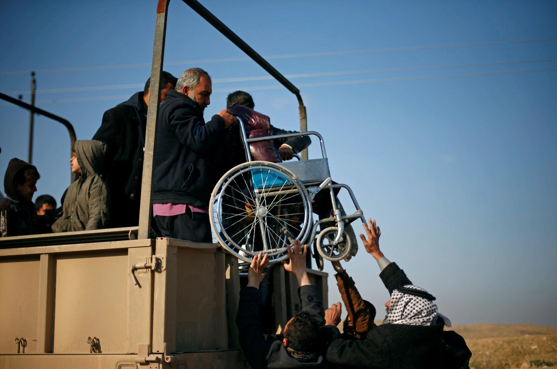 A wheelchair is lifted onto truck as refugees flee