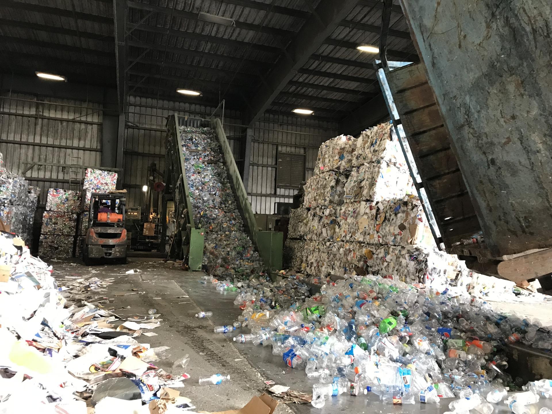 Large collections of plastic are spread out and sorted inside a warehouse. 