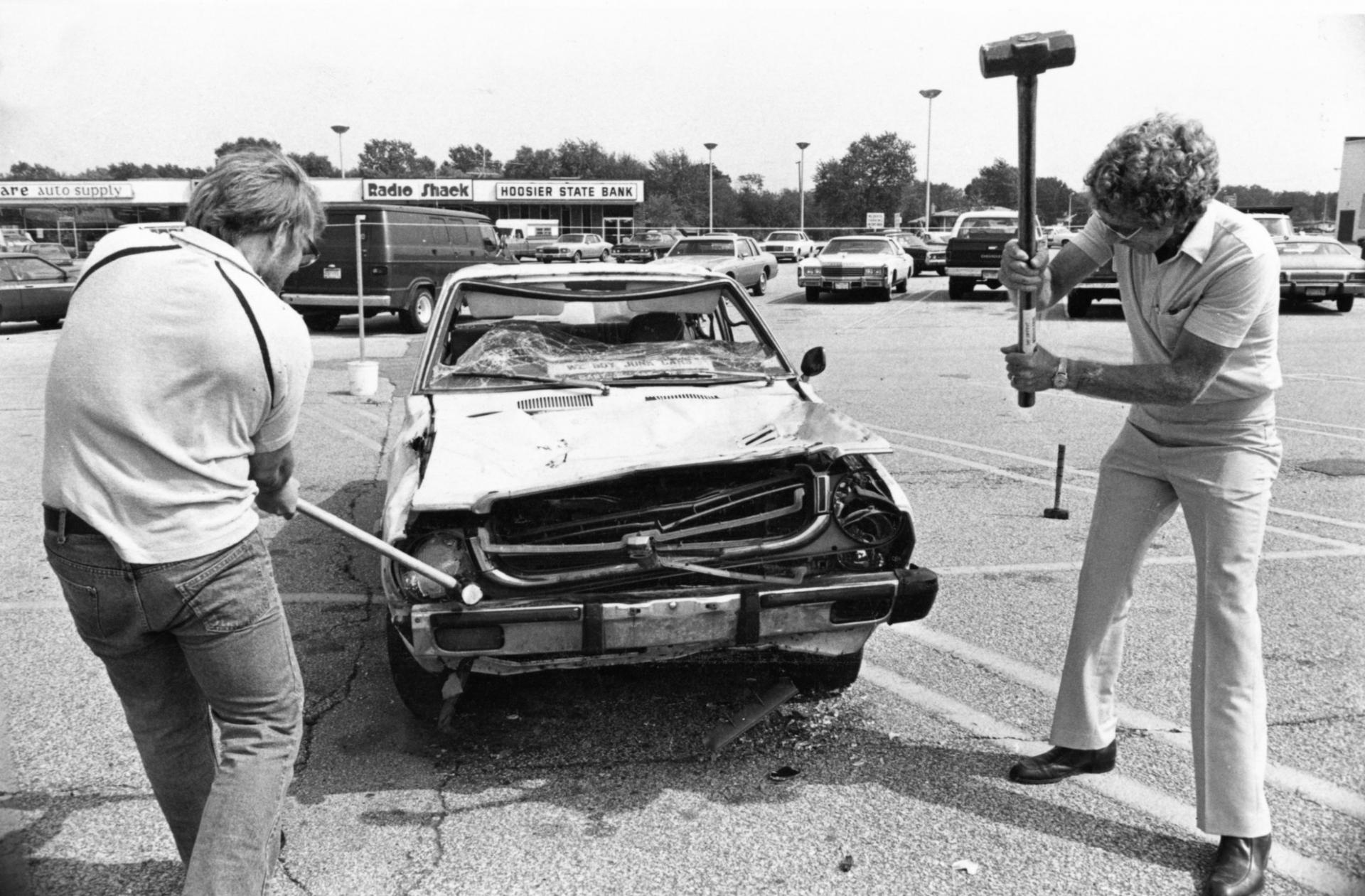 Auto worker Jim Coleman (left) and businessman Charlie Cobb (right) swing sledgehammers in Indiana at a Japanese-made car for $1 a shot. The money went to help the families of laid-off workers, Friday, Sept. 10, 1982.