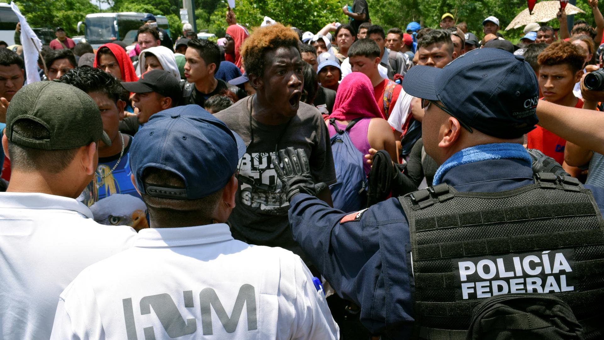 A man confronts a police officer in a dense crowd