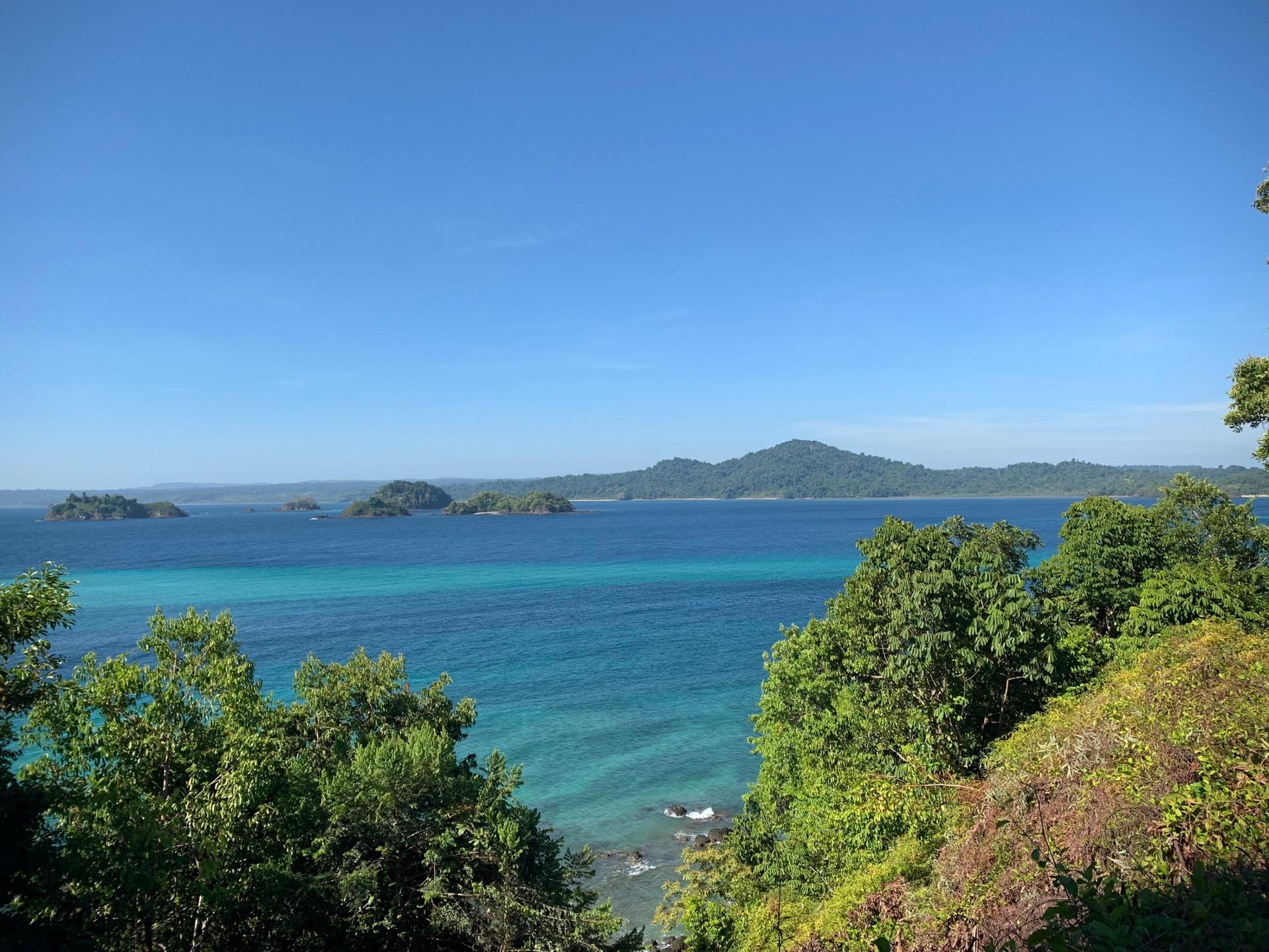 A view of the blue ocean from framed with the lush green forests of Coiba National Park.