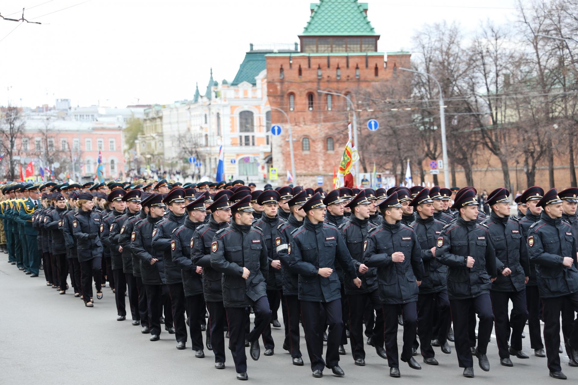 Men in miltary uniforms and formation march down a street