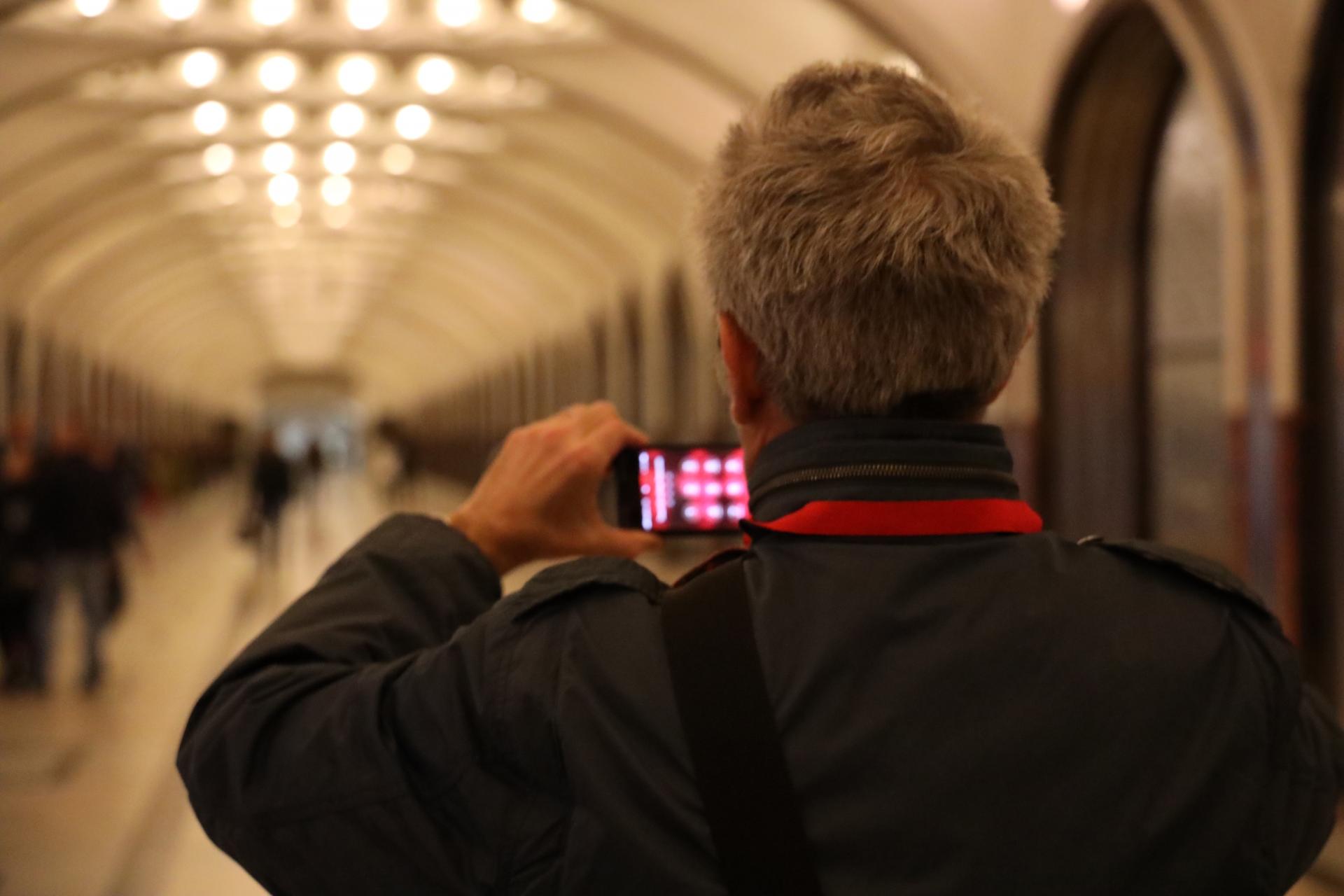 A man takes a photo of a train station on his cell phone